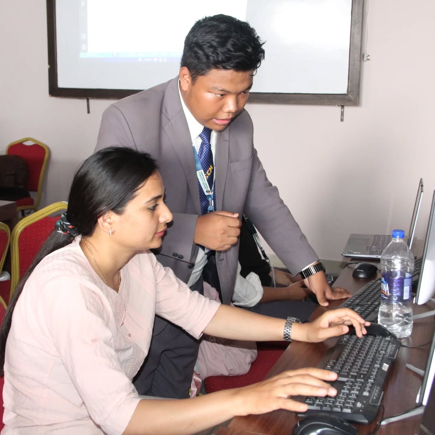 A facilitator helping a participant at a computer during the Beginner-Friendly HTML and CSS Workshop